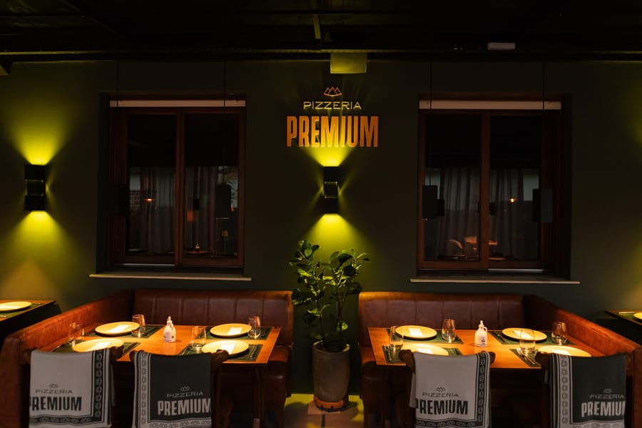 Parede verde com o letreiro iluminado da Pizzeria Premium