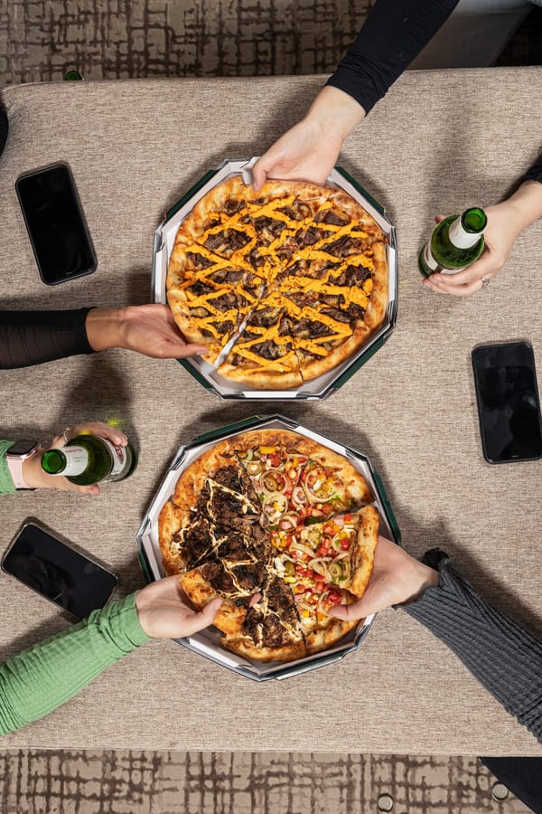 Duas pizzas da Premium nas caixas, sendo divididas entre amigos em casa